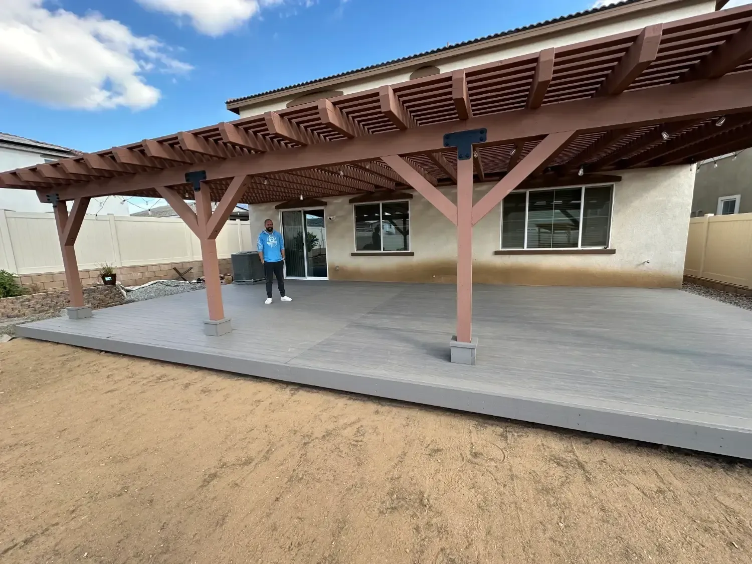 Wood deck with pergola structure, BPP Construction project in Riverside County, featuring a homeowner standing on the deck, showcasing quality craftsmanship and outdoor living space.