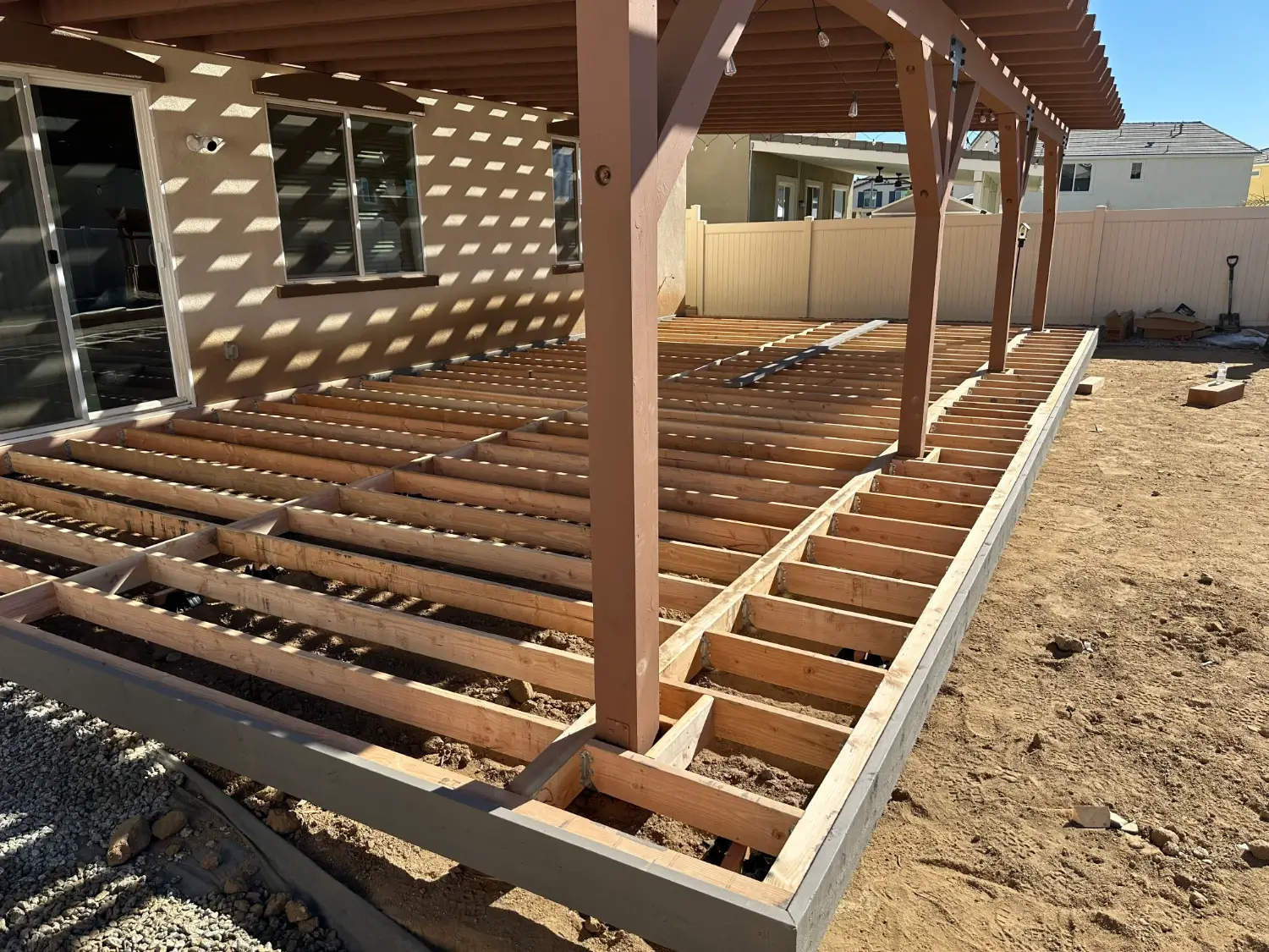 Wooden deck framing under a covered patio, showcasing construction progress for outdoor living space in Norco, CA.