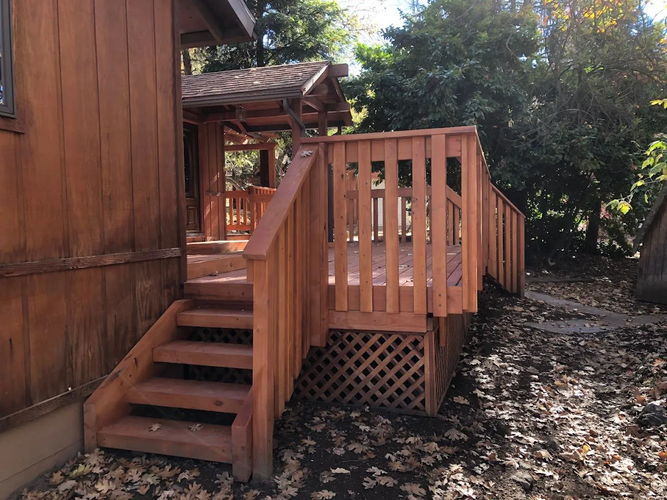 Custom wood deck with railing and stairs, showcasing craftsmanship and design for outdoor living, surrounded by natural landscaping.
