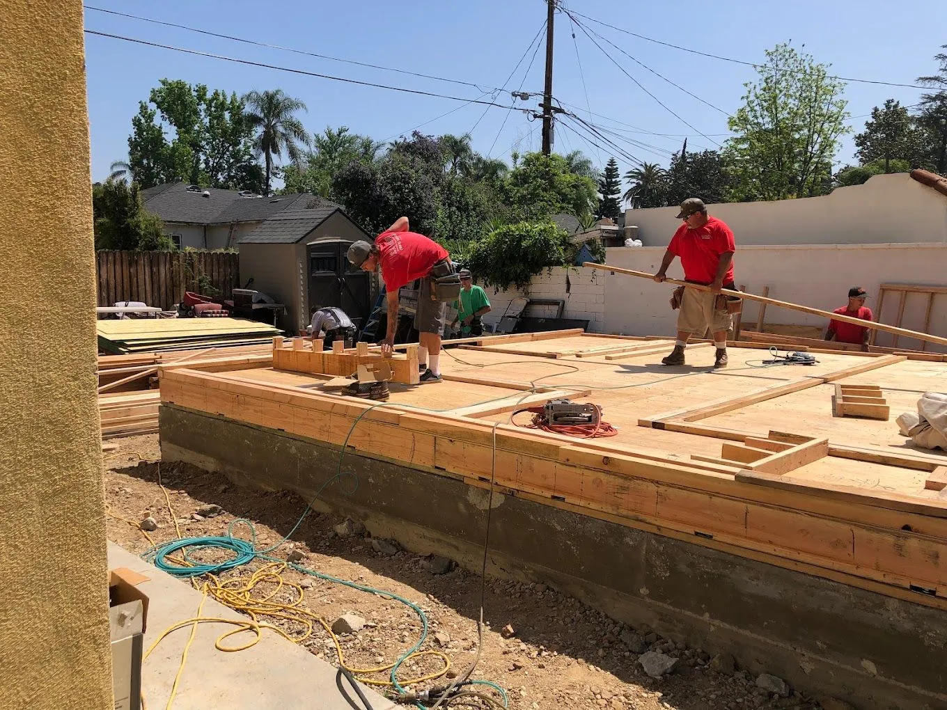 Construction crew working on an accessory dwelling unit (ADU) foundation, featuring wooden framing, tools, and construction materials in a residential setting.