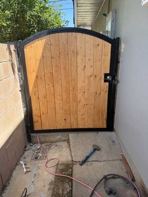 Custom wooden gate with black metal frame installed in a residential setting, showcasing craftsmanship and attention to detail, aligned with BPP Construction's home improvement services.