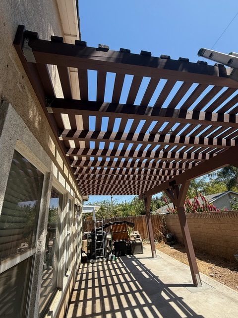 Lattice pergola with dark brown stain, showcasing wood construction in a residential backyard setting, Riverside County project.