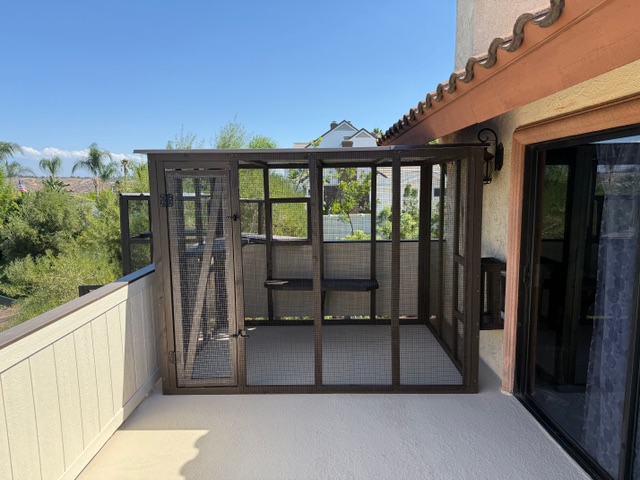 Custom catio on a second-story balcony with metal framing, mesh panels, and a view of surrounding greenery, showcasing BPP Construction's craftsmanship in outdoor structures.