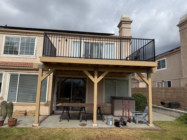 Second-story balcony with metal railing and wooden support structure, overlooking a patio area, part of a residential construction project by BPP Construction in Riverside County.