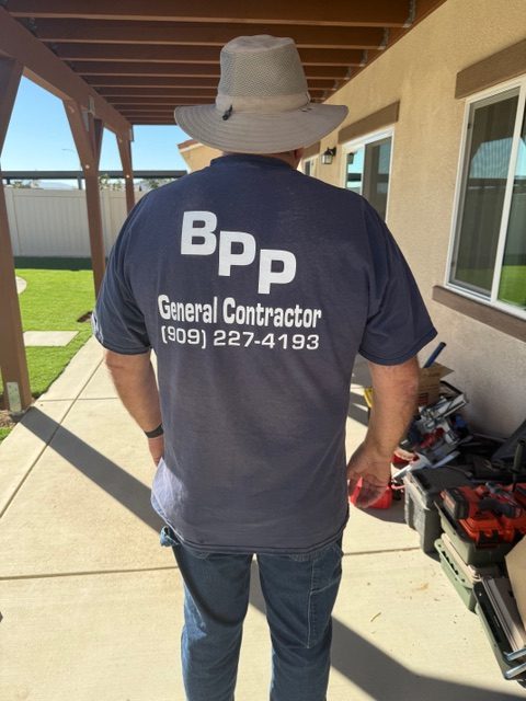 BPP Construction crew member wearing a branded shirt, showcasing general contractor details, in a residential construction site setting.