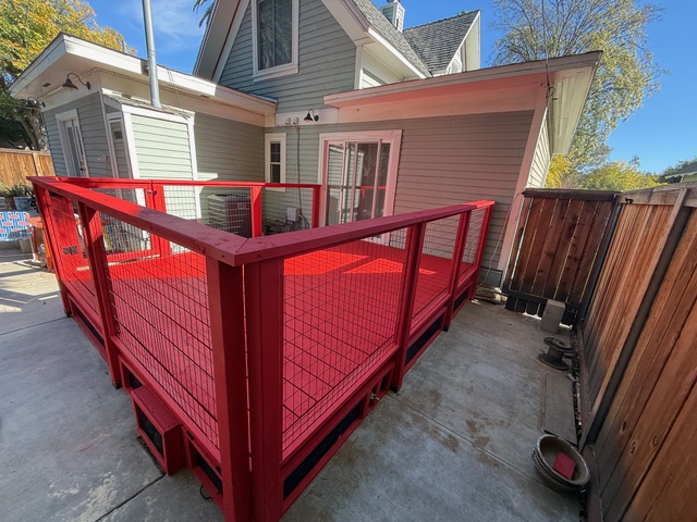Red wood deck with safety railing adjacent to a house, designed for outdoor living, reflecting BPP Construction's residential wood services in Beaumont.